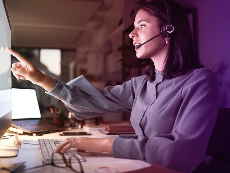 A woman with headphones works on a PC
